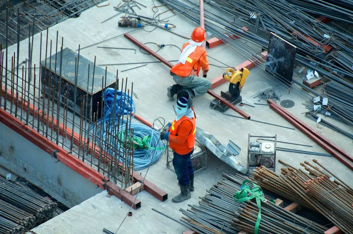 Vista aérea de obra com estrutura de ferragens e trabalhadores